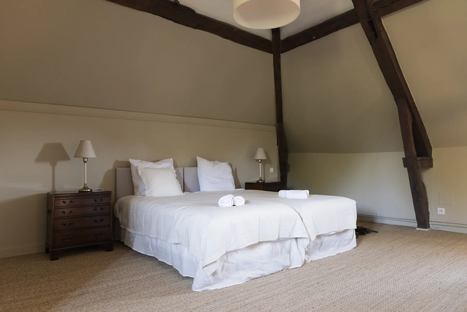La chambre de la Charpente, lit blanc sous les poutres sombres