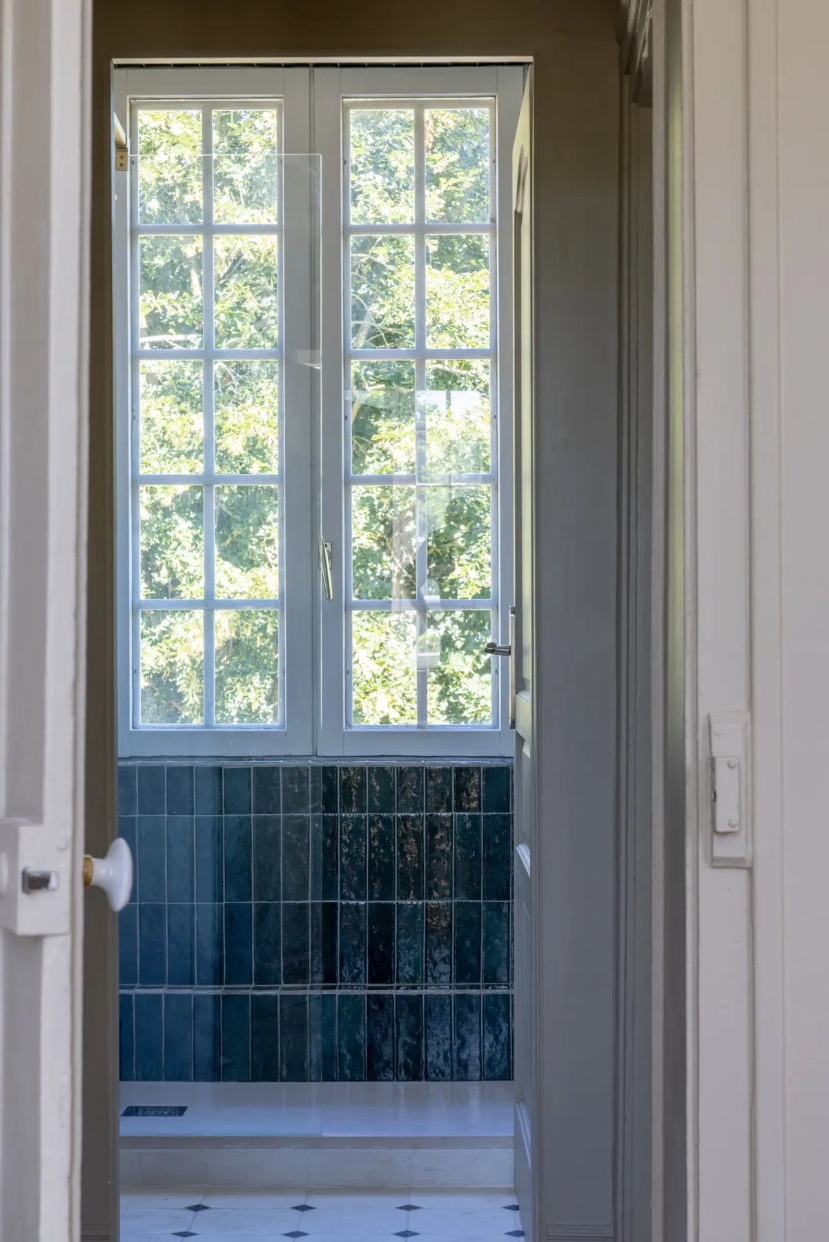 Porte vitrée ouvrant sur la douche en zellige vert